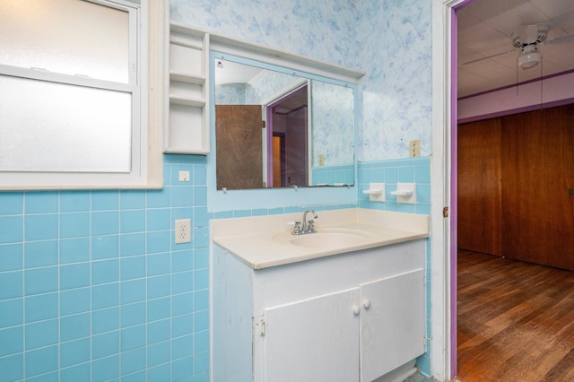 bathroom featuring vanity, ceiling fan, hardwood / wood-style flooring, and tile walls