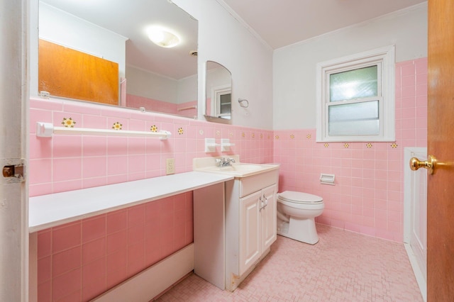 bathroom with toilet, crown molding, tile walls, vanity, and tile patterned flooring