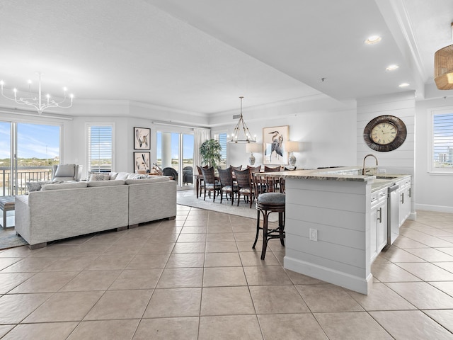 tiled living room featuring ornamental molding, plenty of natural light, sink, and an inviting chandelier