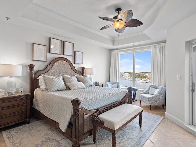 bedroom featuring light tile patterned floors, ornamental molding, a raised ceiling, and a water view