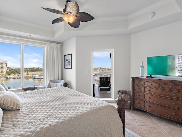 bedroom featuring light tile patterned flooring, a water view, crown molding, a raised ceiling, and ceiling fan