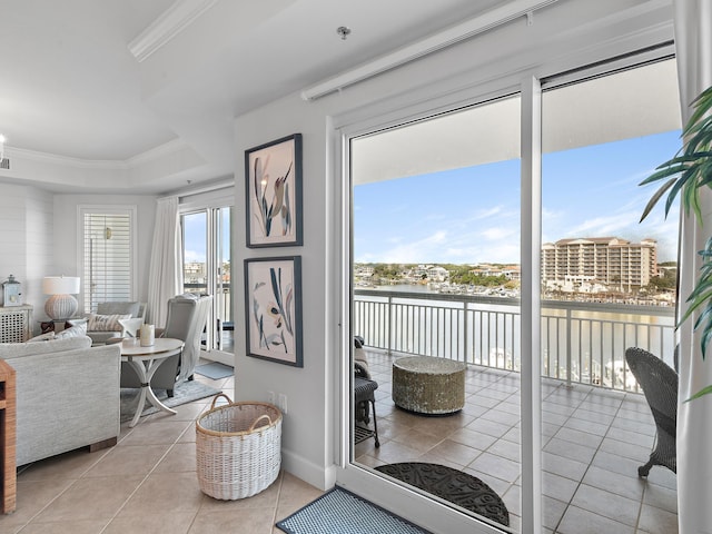 interior space with crown molding, a water view, a raised ceiling, and light tile patterned floors