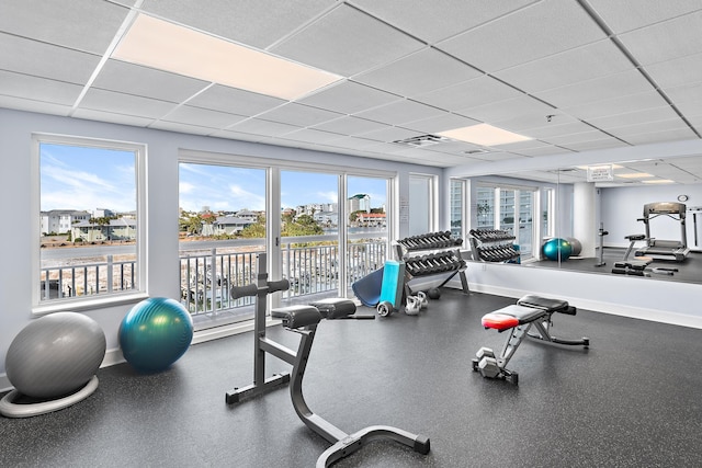 gym featuring a paneled ceiling and a wealth of natural light