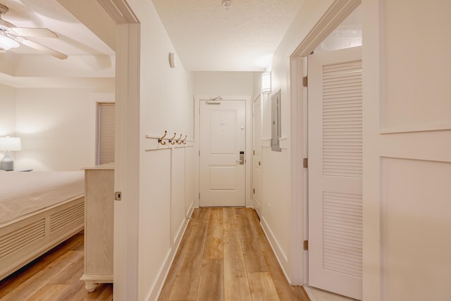 corridor featuring a textured ceiling and light hardwood / wood-style flooring