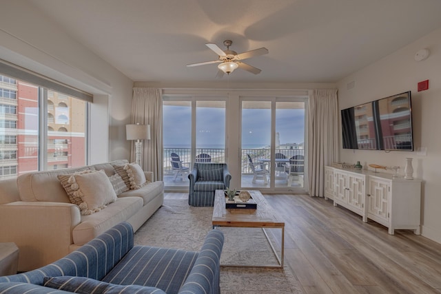 living room with a wealth of natural light, ceiling fan, and light hardwood / wood-style flooring