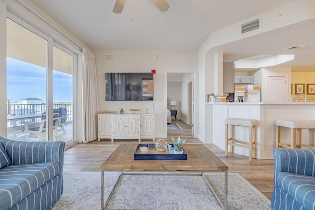 living room with ceiling fan, sink, and light hardwood / wood-style flooring