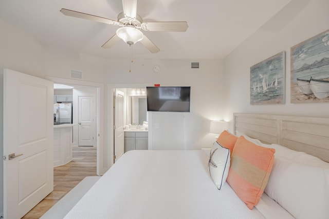 bedroom featuring ceiling fan, ensuite bathroom, stainless steel fridge with ice dispenser, and light wood-type flooring