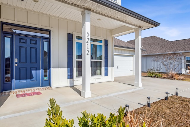 doorway to property featuring driveway, a porch, board and batten siding, and roof with shingles