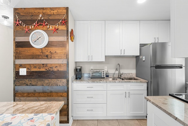 kitchen featuring sink, white cabinets, and stainless steel refrigerator