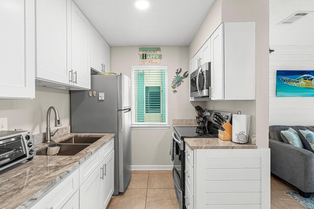 kitchen featuring appliances with stainless steel finishes, white cabinetry, sink, light tile patterned floors, and light stone counters