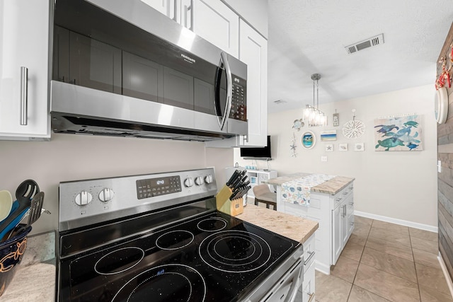 kitchen featuring light tile patterned flooring, pendant lighting, white cabinets, stainless steel appliances, and a textured ceiling