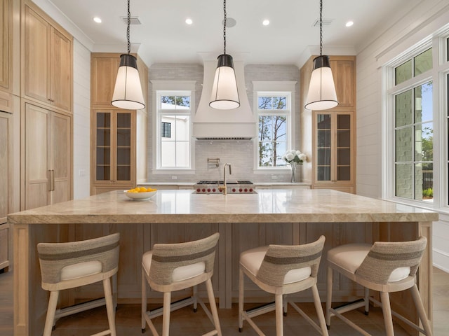 kitchen featuring premium range hood, decorative light fixtures, a kitchen breakfast bar, a large island, and decorative backsplash