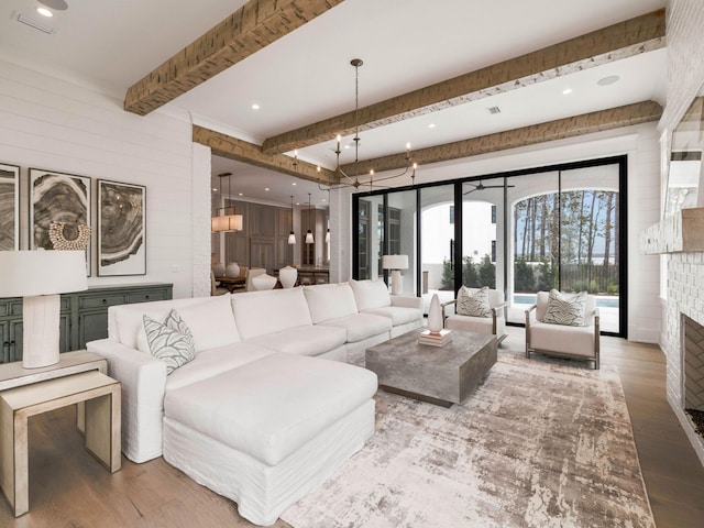 living room with beamed ceiling, wood-type flooring, and a brick fireplace