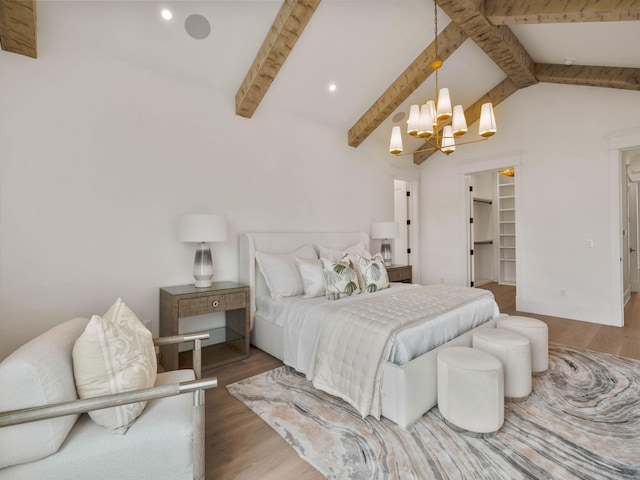 bedroom featuring a walk in closet, dark hardwood / wood-style floors, lofted ceiling with beams, and a notable chandelier