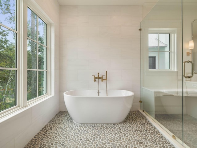 bathroom featuring tile walls, plenty of natural light, and separate shower and tub