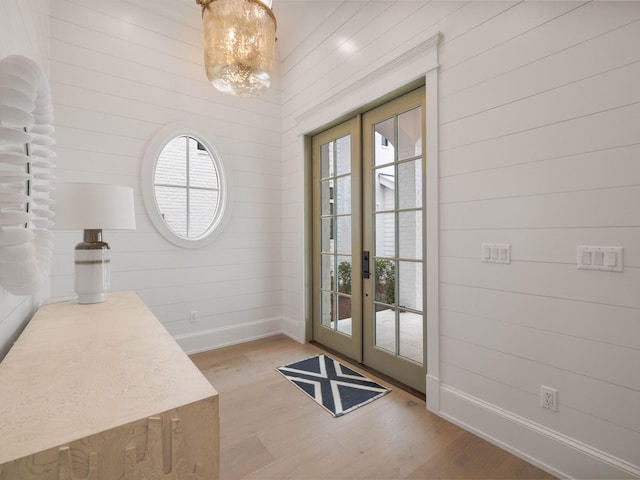 doorway with a notable chandelier, light hardwood / wood-style floors, and french doors