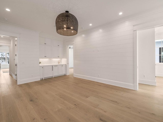 unfurnished living room featuring crown molding and light wood-type flooring