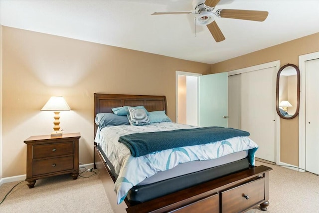 bedroom featuring light carpet, two closets, and ceiling fan