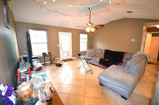 living room with a wealth of natural light, vaulted ceiling, ceiling fan, and light tile patterned flooring