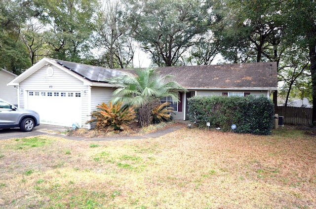 ranch-style house featuring a garage, a front yard, and solar panels