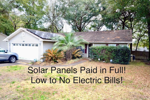 ranch-style house with a garage, a front lawn, and solar panels