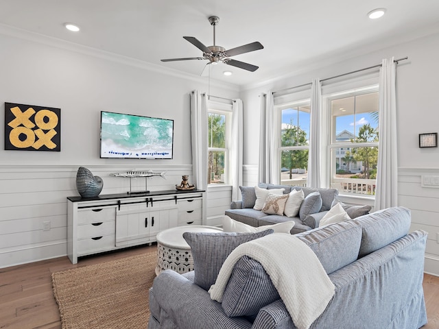 living room with wood-type flooring, ornamental molding, and ceiling fan