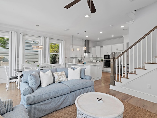 living room featuring crown molding, ceiling fan, and light wood-type flooring