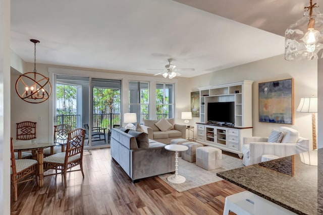 living room with ceiling fan with notable chandelier, a healthy amount of sunlight, and hardwood / wood-style floors