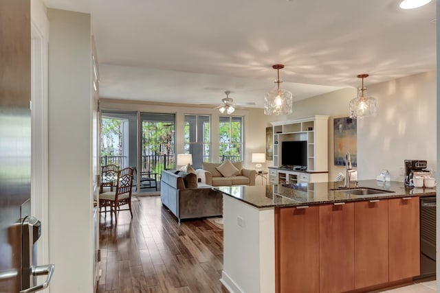 kitchen with a wealth of natural light, sink, dark stone countertops, and decorative light fixtures