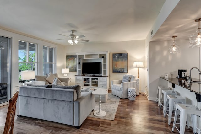 living room with dark hardwood / wood-style floors, sink, and ceiling fan