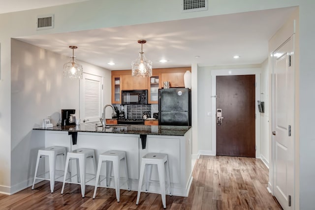 kitchen with pendant lighting, a kitchen breakfast bar, black appliances, and kitchen peninsula