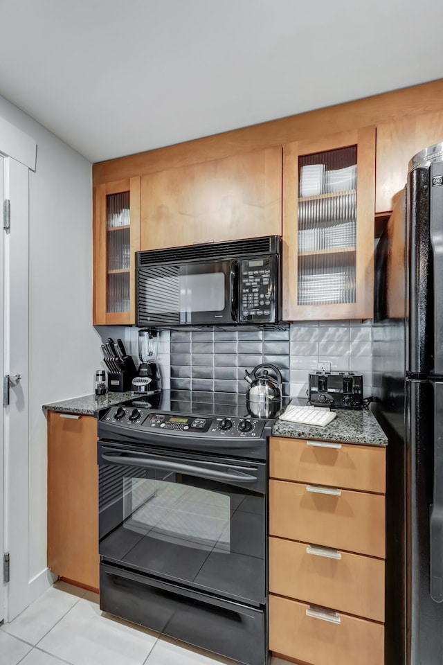 kitchen with tasteful backsplash, black appliances, dark stone counters, and light tile patterned flooring