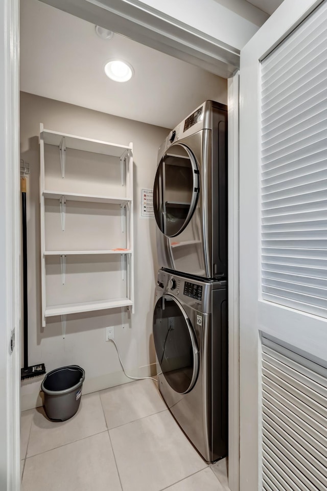 washroom with stacked washing maching and dryer and light tile patterned floors