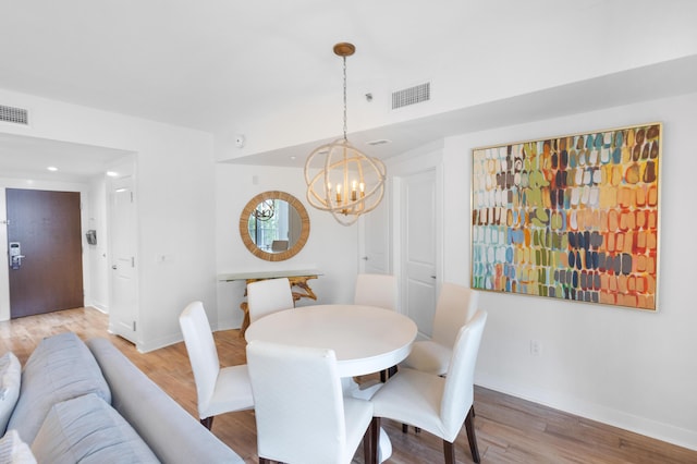 dining area with hardwood / wood-style floors and a notable chandelier