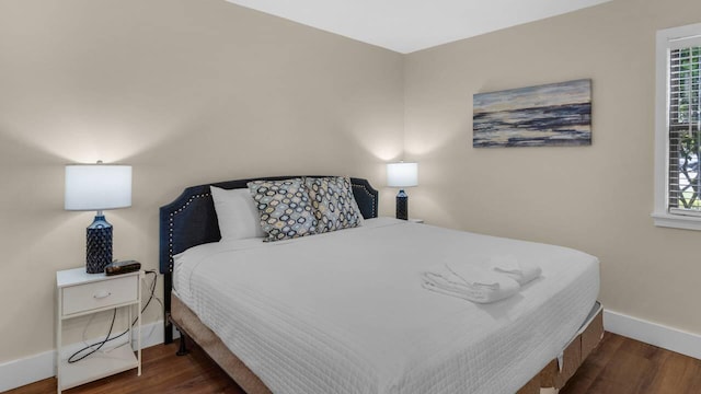 bedroom with multiple windows and dark hardwood / wood-style flooring