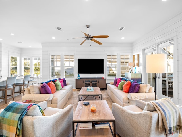 living room featuring wood-type flooring, a healthy amount of sunlight, and ceiling fan