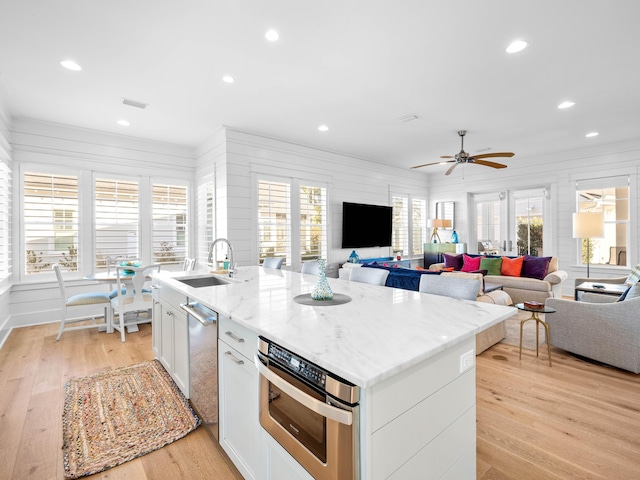 kitchen featuring sink, a center island with sink, white cabinets, and light hardwood / wood-style flooring