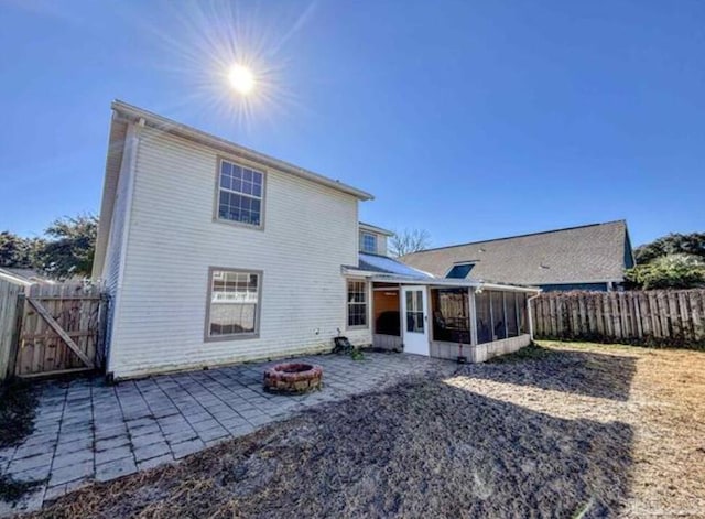 rear view of house with a sunroom, a patio area, and an outdoor fire pit