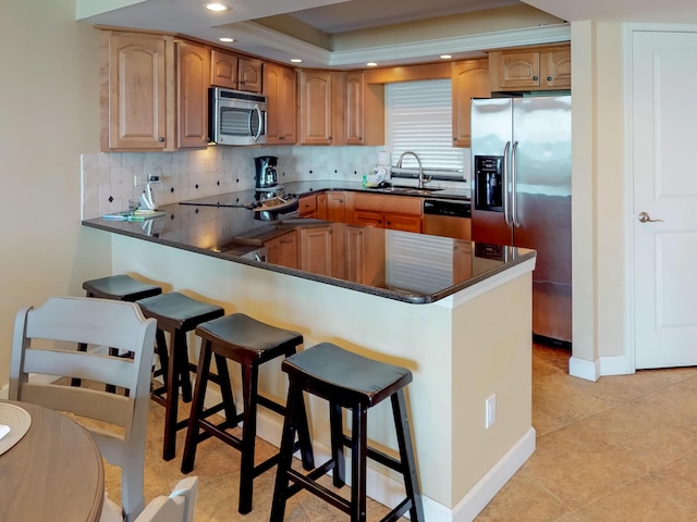 kitchen featuring sink, appliances with stainless steel finishes, tasteful backsplash, a raised ceiling, and kitchen peninsula