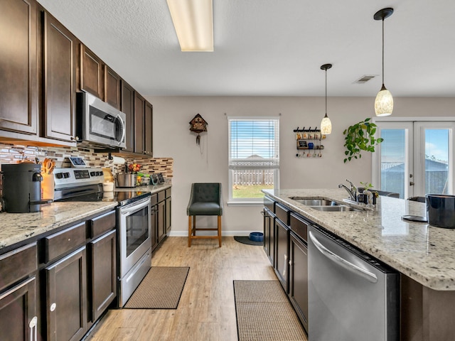 kitchen featuring dark brown cabinetry, sink, appliances with stainless steel finishes, pendant lighting, and backsplash