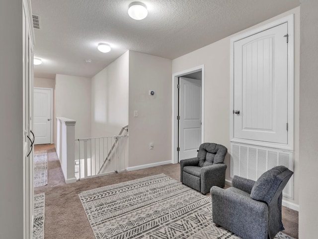 sitting room with light carpet and a textured ceiling