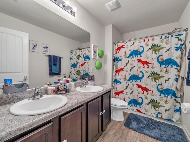 bathroom featuring curtained shower, hardwood / wood-style flooring, vanity, toilet, and a textured ceiling