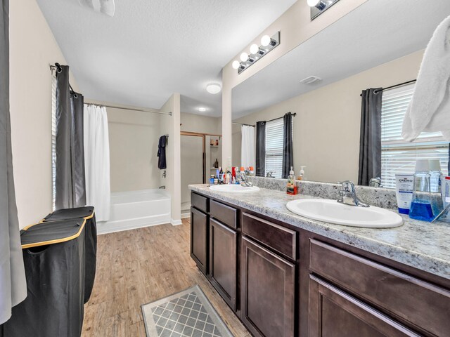 bathroom featuring hardwood / wood-style flooring, vanity, a wealth of natural light, and shower / bath combo