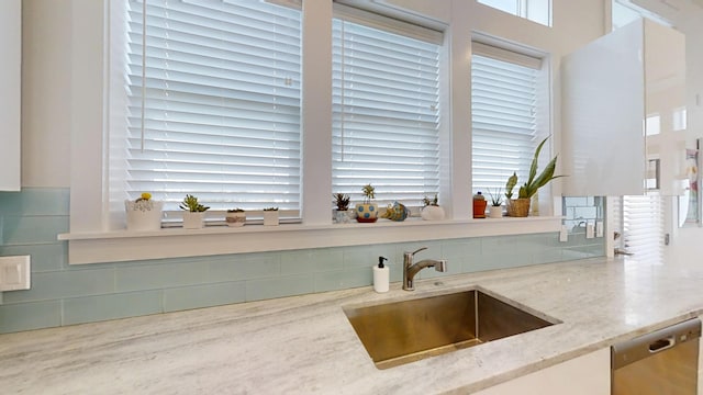 kitchen with light stone counters, stainless steel dishwasher, and sink