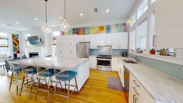 kitchen featuring a kitchen island, stainless steel appliances, white cabinets, and a kitchen bar