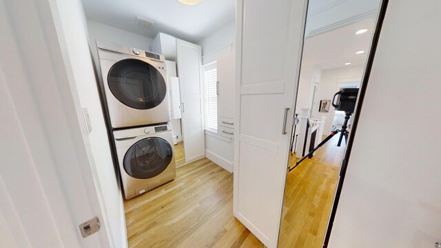 washroom with stacked washer / dryer and light hardwood / wood-style floors