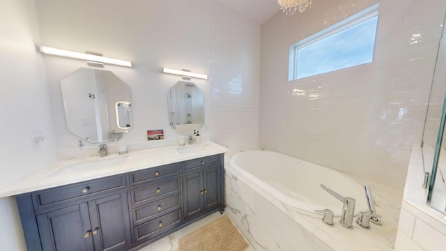 bathroom with vanity, tiled bath, and an inviting chandelier