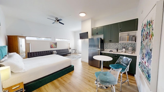 bedroom featuring stainless steel refrigerator and light hardwood / wood-style floors