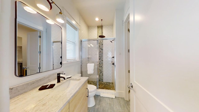 bathroom featuring wood-type flooring, toilet, a shower with door, and vanity