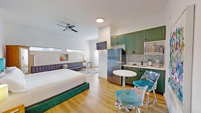 bedroom with sink, light hardwood / wood-style floors, and stainless steel refrigerator